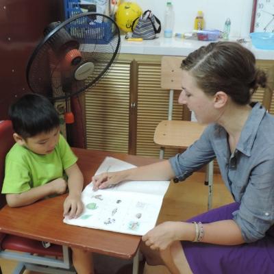 Projects Abroad intern giving reading lessons to a young boy in asia whilst on her speech therapy internship in Vietnam. A Projects Abroad intern is seen helping a young boy read during her speech therapy internship in Vietnam.